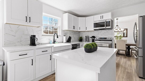 A modern kitchen with white cabinetry, a marble countertop, a built-in oven, and a stainless steel refrigerator. - Luxury Fishers,IN Home - 4BR • Fully Renovated • Finished Basement • WiFi (Fishers)