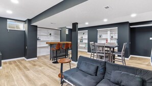A modern living room with a gray sofa, wooden dining table, and chairs. - Luxury Fishers,IN Home - 4BR • Fully Renovated • Finished Basement • WiFi (Fishers)