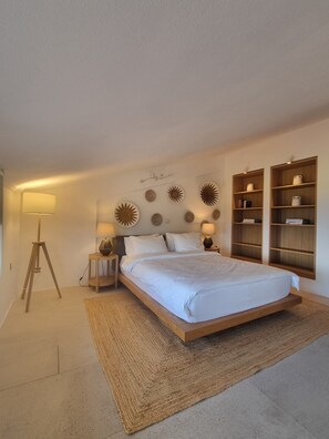 A bedroom with a bed, bedside tables, a floor lamp, wall decor, and built-in shelving. - Villa Muse Sea View and private Pool (Afitos)