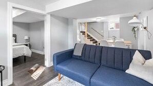 Un soggiorno moderno con un divano blu, una scala e un'area pranzo.