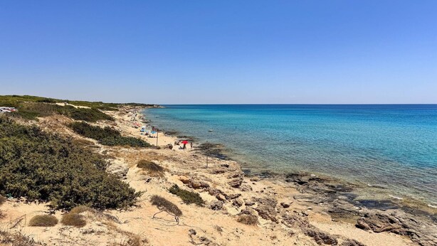 A beach with clear water, sandy shore, and sparse vegetation. - Marubium - Scorcialupi (Maruggio)