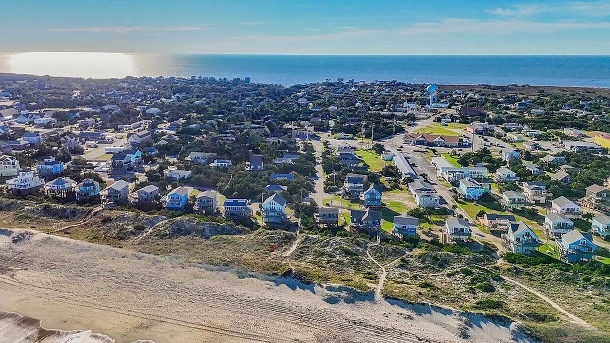 A coastal residential area with houses, a beach, and a water tower.