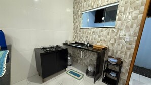 Una cocina compacta con estufa a gas, un lavamanos y una pequeña encimera.