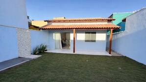 Una casa con techo de tejas, un pequeño jardín y una puerta visible que da a un espacio interior.