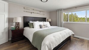 A bedroom with a bed, nightstands, a window with a view, and a ceiling with a light fixture. - Private Lakefront House, 15 feet to water, Kayaks, Game Room, Dog Friendly (Wolverine)