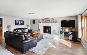 Un salon avec une cheminée, un canapé, une table basse et un téléviseur.