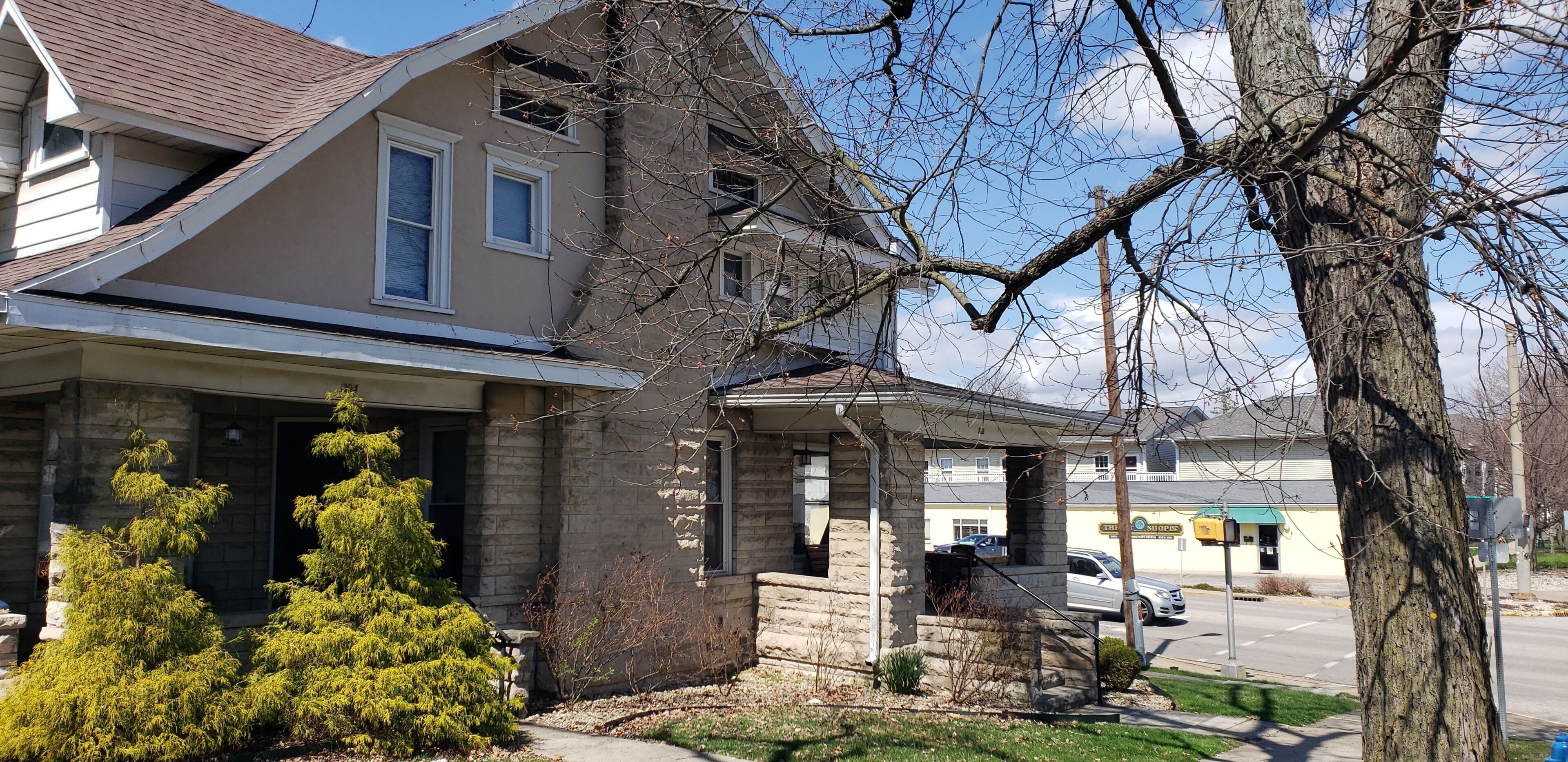 A two-story house with a stone facade, a front porch, and a driveway.