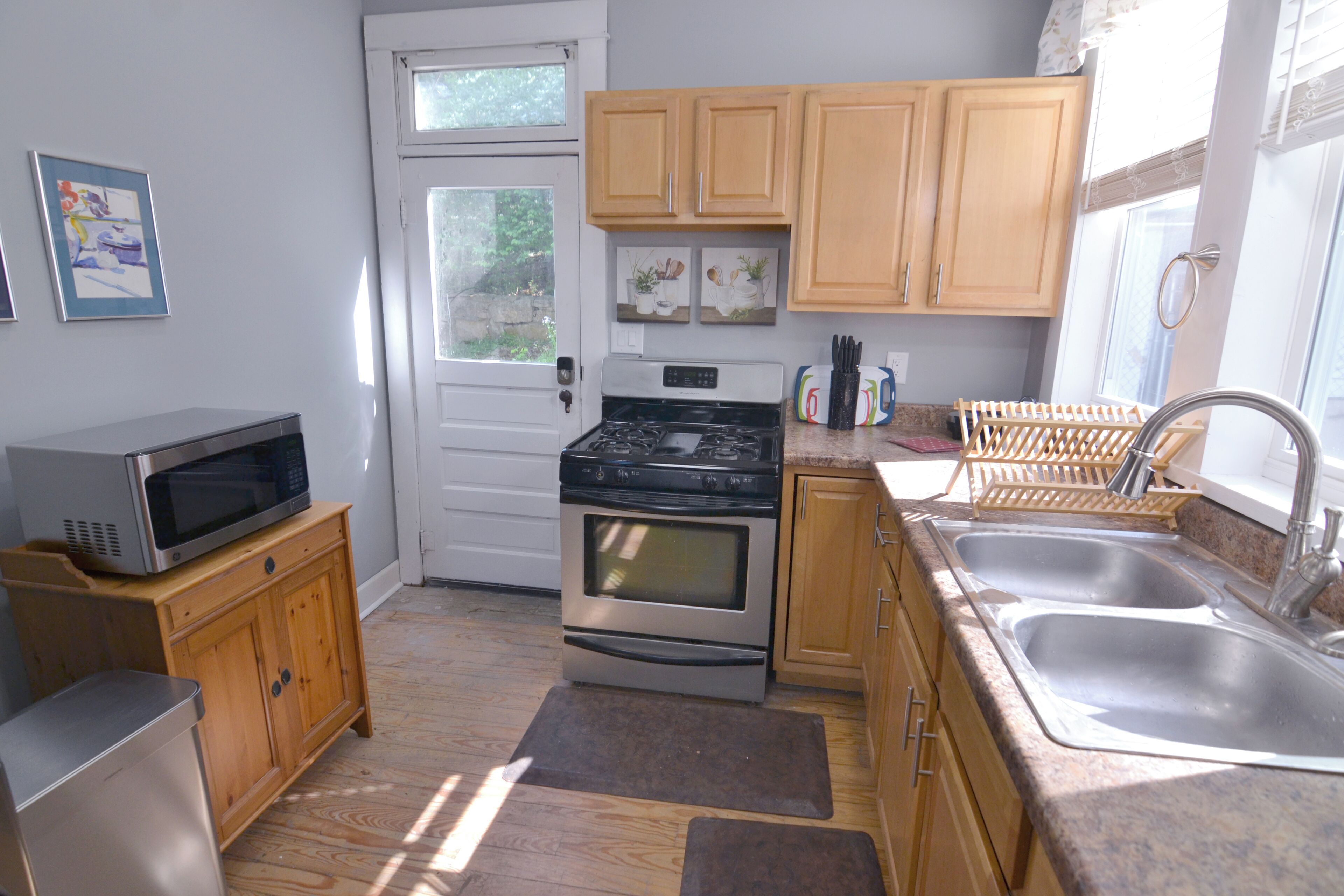 A compact kitchen with wooden cabinets, a microwave, stove, and a sink.