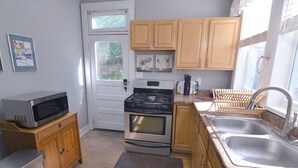 Una cocina compacta con armarios de madera, microondas, estufa y lavaplatos.
