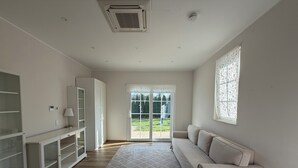 Ein modernes Zimmer mit einem weißen Sofa, einer Glastruhe, einem gemusterten Teppich und einer Schiebeglas-Tür, die zu einem Außenbereich führt.