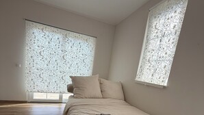 Ein Schlafzimmer mit Bett, Teppich und Fenster mit gemustertem Vorhang.