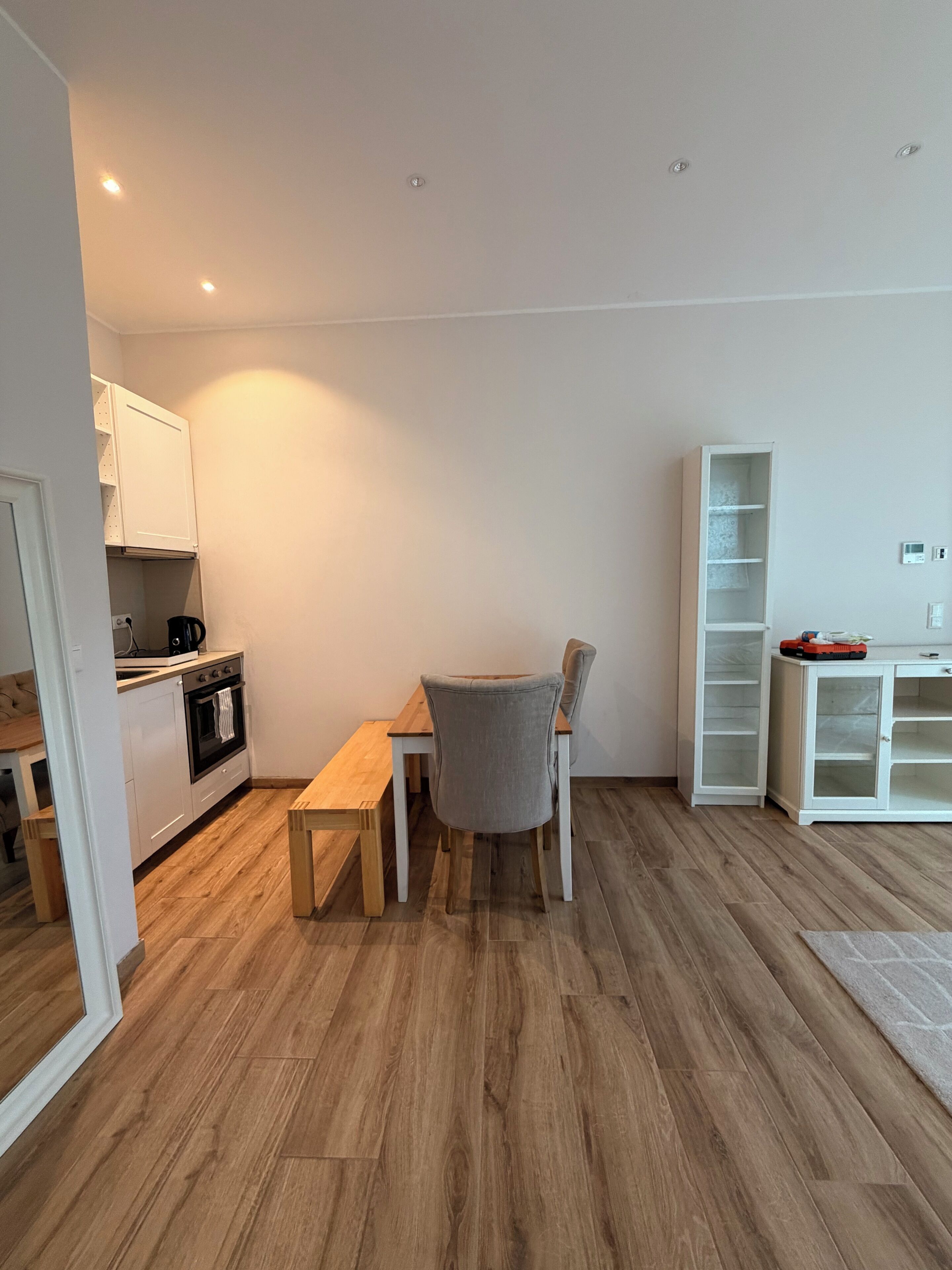 Eine moderne Küche mit weißen Schränken, einem Holztisch und einem grauen Stuhl.