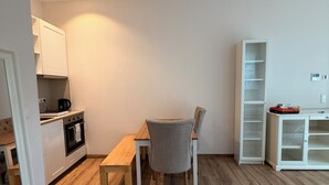 Eine moderne Küche mit weißen Schränken, einem Holztisch und einem grauen Stuhl.