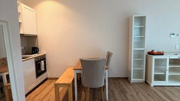 Eine moderne Küche mit weißen Schränken, einem Holztisch und einem grauen Stuhl.