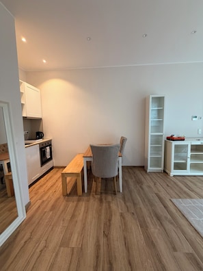 Eine moderne Küche mit weißen Schränken, einem Holztisch und einem grauen Stuhl.