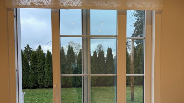 Ein Zimmer mit einer großen Schiebetür zu einer Terrasse, einem Bett mit weißer Bettdecke und Holzboden.