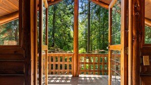 Una cabaña de madera con un balcón que da a un bosque.