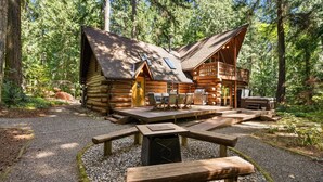 Una cabaña de madera con terraza, mobiliario exterior y mesa de picnic.