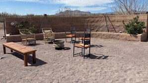 Un patio al aire libre con un banco de madera, sillas de mimbre y sillas de metal.