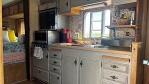 Una cocina compacta para autocaravana con microondas, estufa, lavabo y armarios de almacenamiento.