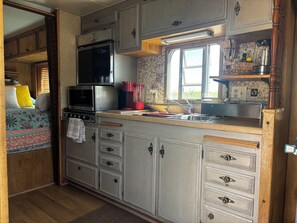 Una cocina compacta para autocaravana con microondas, estufa, lavabo y armarios de almacenamiento.