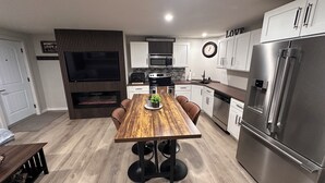 Een moderne keuken met een houten eettafel, een inbouwoven, een magnetron en een roestvrijstalen koelkast.