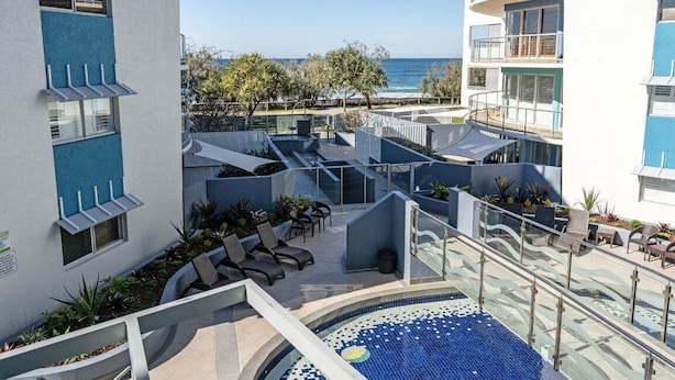 Área de piscina no terraço com espreguiçadeiras, uma piscina pequena e vista para o oceano.
