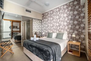A bedroom with a bed, a nightstand, a lamp, a wardrobe, and a sliding door leading to a balcony.