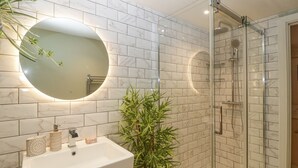 A bathroom with a white sink, two round mirrors, and a glass shower enclosure. - Charming apartment set in the Wye Valley, Herefordshire (Perrystone Hill, Ross-on-Wye)