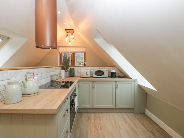 A kitchen with a wooden countertop, a stove, a microwave, and cabinets.
