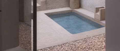 A concrete staircase leading to a small pool with pebbles at the bottom.