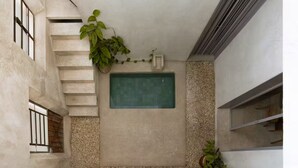 A small, enclosed space with a green tiled feature, a staircase, and a plant. - Meridiano 48 Loft, One-Bedroom Accommodation (Mérida)