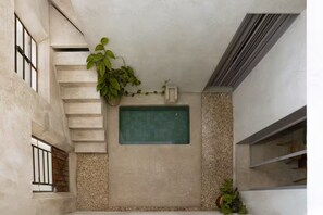 Ein kleiner, abgeschlossener Raum mit einer grünen Fliesenwand, einer Treppe und einer Pflanze.