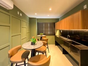A compact kitchen with a dining area, featuring a round table, chairs, and a built-in stove. - Saint Bartz Residence - Ondina (Salvador)
