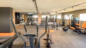 A gym with exercise equipment, a mirrored wall, and a view into another room. - Saint Bartz Residence - Ondina (Salvador)