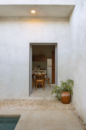 Ein kleiner, abgeschlossener Patio-Bereich mit Betonboden, einem Blumentopf und einer Tür zu einer Küche mit Holzmöbeln.