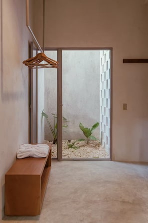 Ein Zimmer mit einer Bank, einem Holzaufhänger, einer Pflanze und Blick durch eine Glastür.