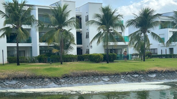 Ein modernes Hotel mit mehreren Etagen, Palmen und einem Wasserspiel.