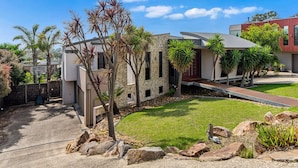 A modern house with a stone facade, a paved driveway, and a well-maintained lawn. - The Ultimate Family Entertainer. Bay Views, Spa & Games (Mount Martha)