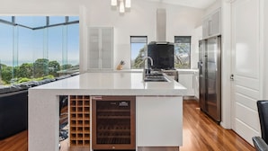 A modern kitchen with a large island, stainless steel appliances, and a wine cooler. - The Ultimate Family Entertainer. Bay Views, Spa & Games (Mount Martha)