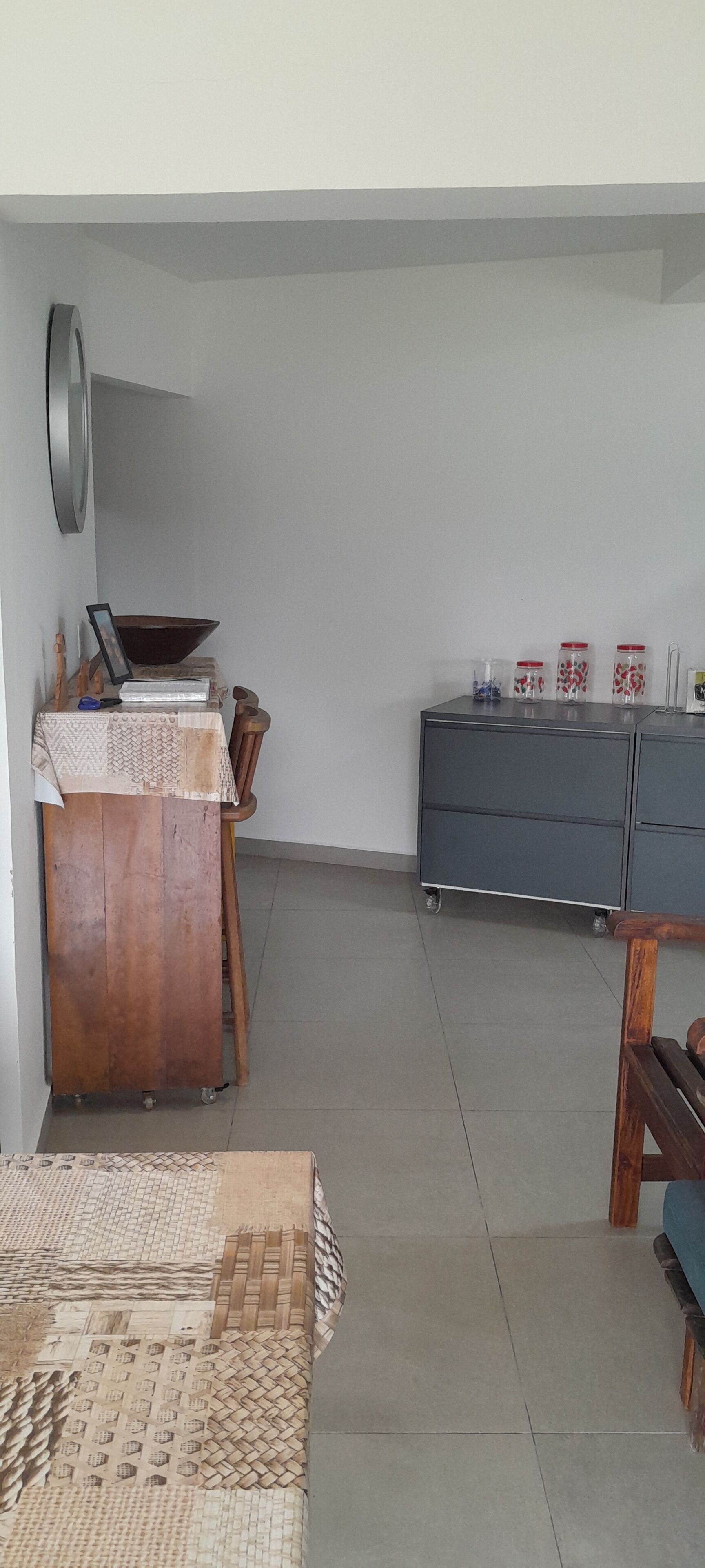 Una habitación con una mesa de madera, un armario con frascos y un piso de baldosas.