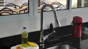 A kitchen with a sink, a window, and a red kettle. - House with a large and cozy pool, with space for the whole family, 100m from the beach. (Itanhaém)