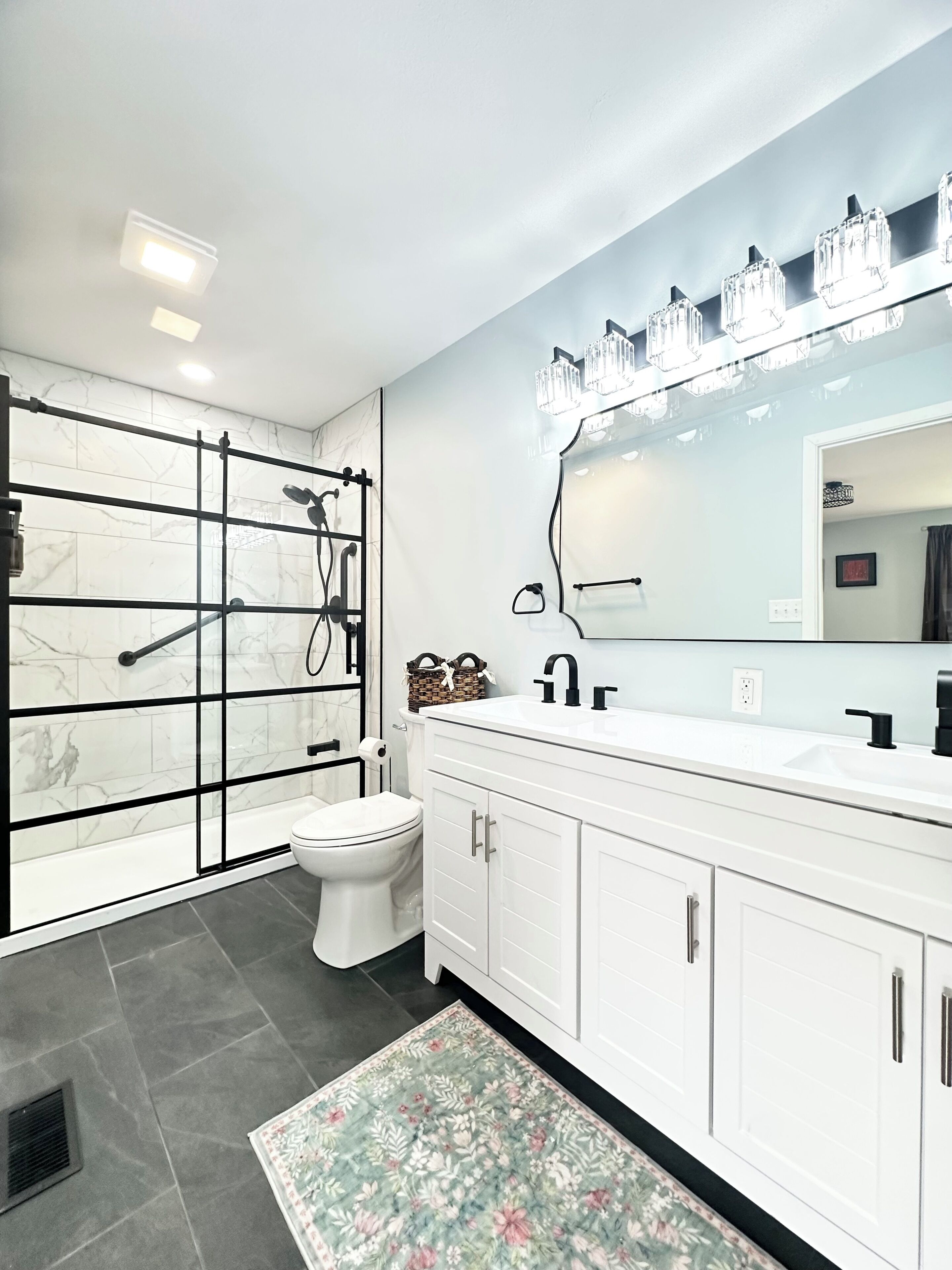 A modern bathroom with a walk-in shower, a toilet, a sink with a mirror, and cabinets.
