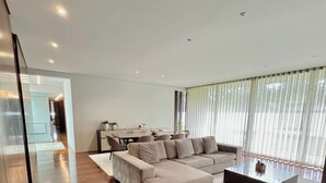 Un salon moderne avec un canapé d’angle, une table basse et un coin repas à l’arrière-plan.