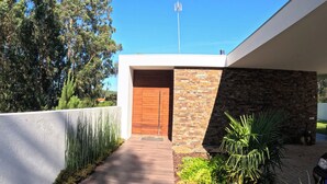 Un bâtiment moderne avec une porte en bois, un mur en pierre et un ciel d’un bleu éclatant.