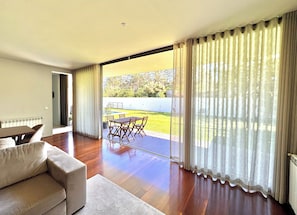 A spacious living room with a large sliding glass door leading to an outdoor area with a pool and garden.