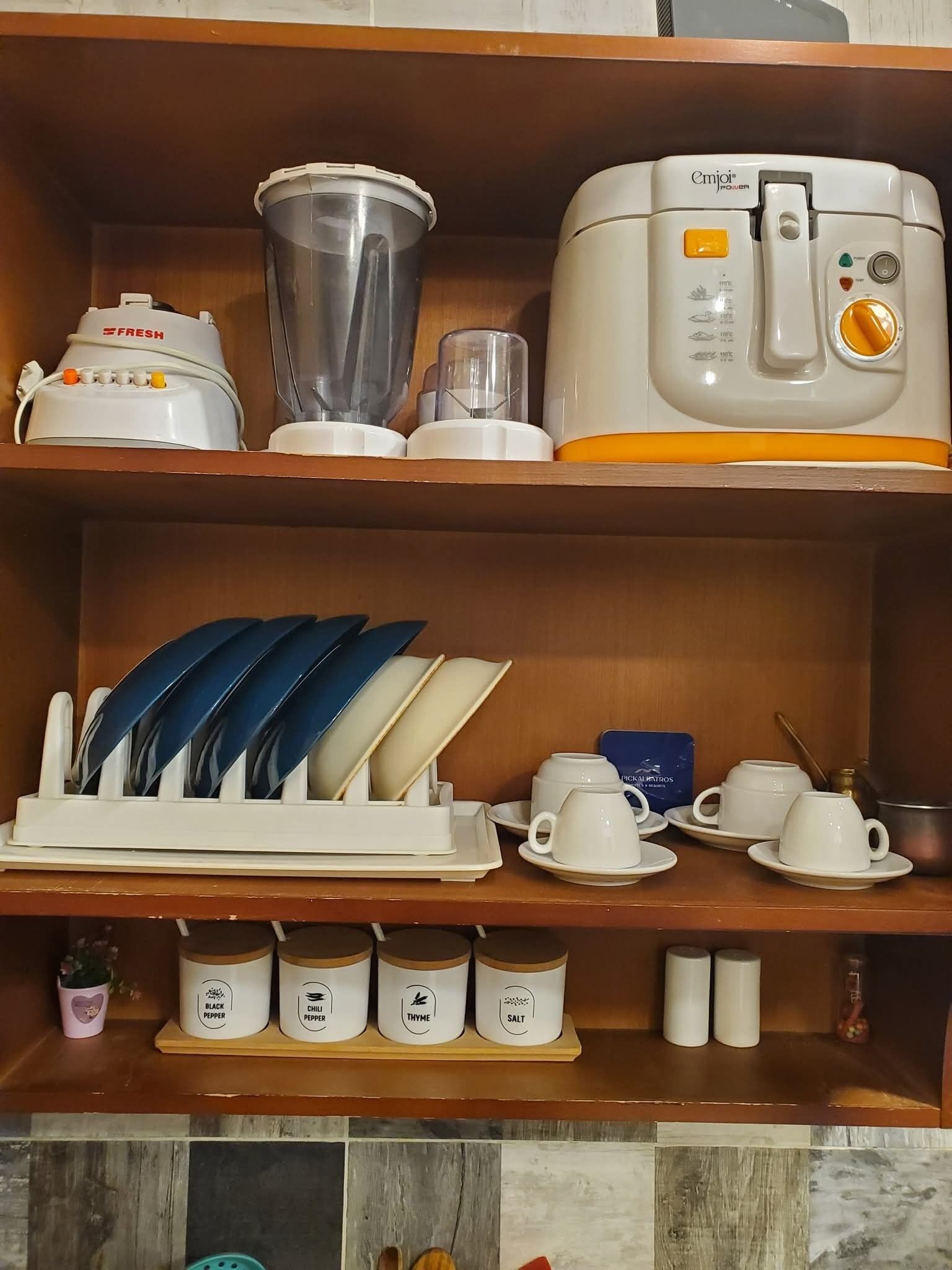 A kitchen with a blender, a rice cooker, and a dish rack with utensils.