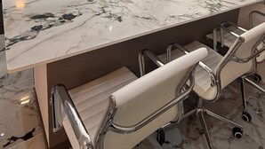 Une cuisine moderne dotée d’un plan de travail en marbre, d’appareils électroménagers en acier inoxydable et d’un coin bar avec des sièges.