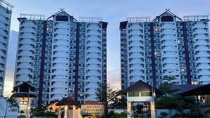 Un immeuble résidentiel de grande hauteur doté de nombreux balcons, d’une entrée sécurisée et d’une enseigne indiquant « ROYAL OCEANCREST ».
