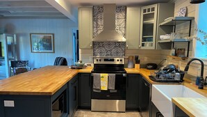 Una cocina funcional con encimera de madera, electrodomésticos de acero inoxidable y salpicadero estampado.